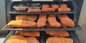 An assortment of meats that have been seasoned and are ready to be smoked.