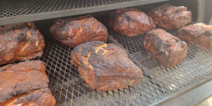 Smoked pork butts on racks being cooked.
